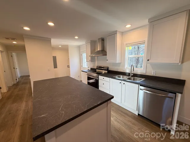 a kitchen with granite countertop a sink a stove and cabinets