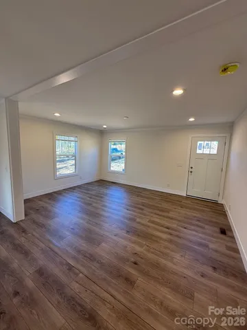 a view of empty room with window and wooden floor