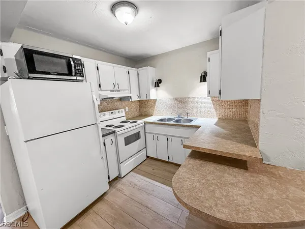 a kitchen with granite countertop white cabinets and white appliances