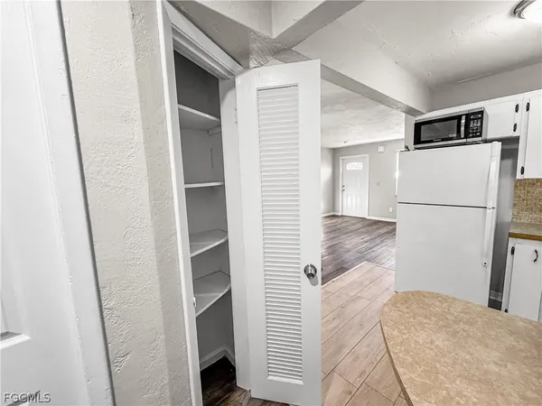 a view of a refrigerator in kitchen and an empty room