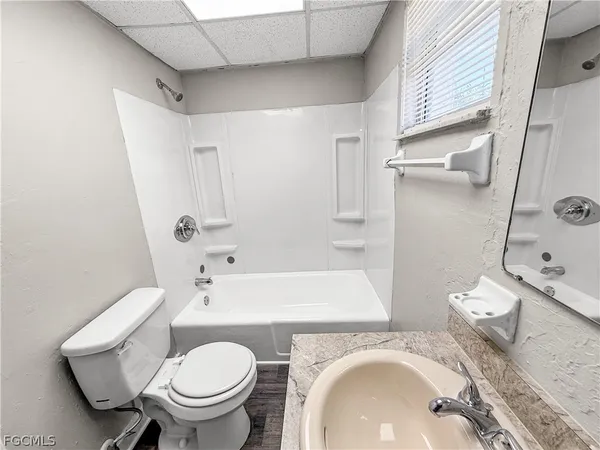a white toilet sitting next to a bathroom sink and a window