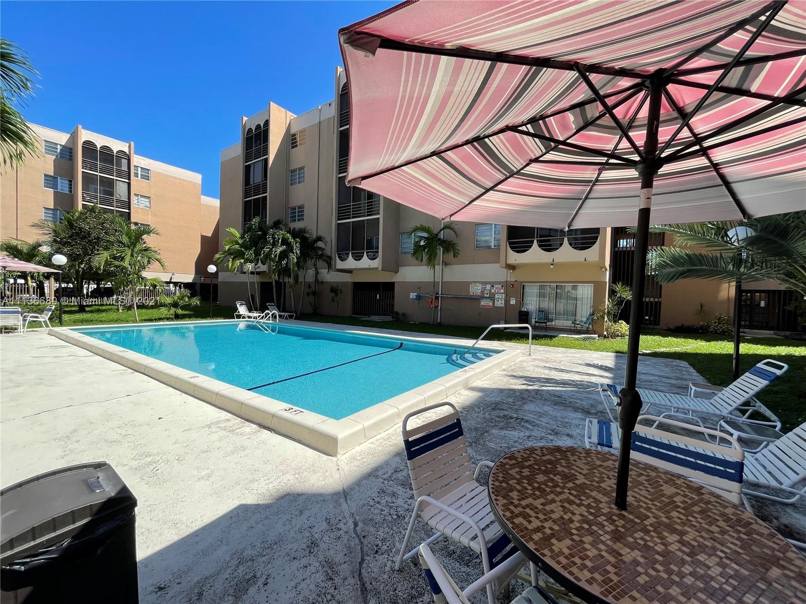 4670 West 13th Lane, Unit 210 Hialeah, FL 33012 - Photo 2 of 11 a patio with a table and chairs under an umbrella