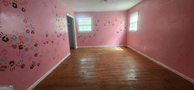a view of a hallway with wooden floor and a bathroom