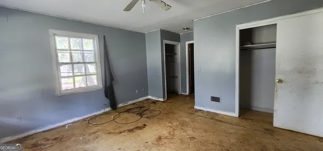 an empty room with closet and a chandelier fan