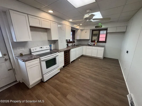 a kitchen with stainless steel appliances white cabinets a sink a stove a refrigerator and a microwave