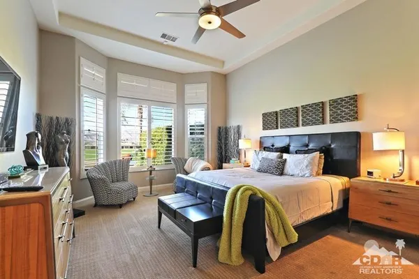 a bedroom with a bed couches and a flat tv screen