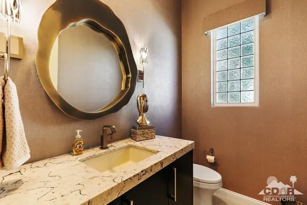a bathroom with a granite countertop toilet a sink and a mirror