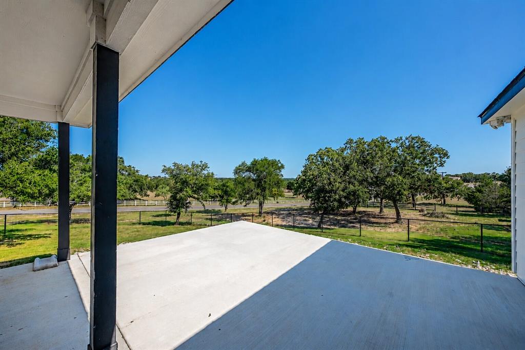 117 Rock Salt Drive Springtown, TX 76082 - Photo 33 of 38 Expansive concrete patio area beneath a covered porch, featuring black support columns and a white ceiling