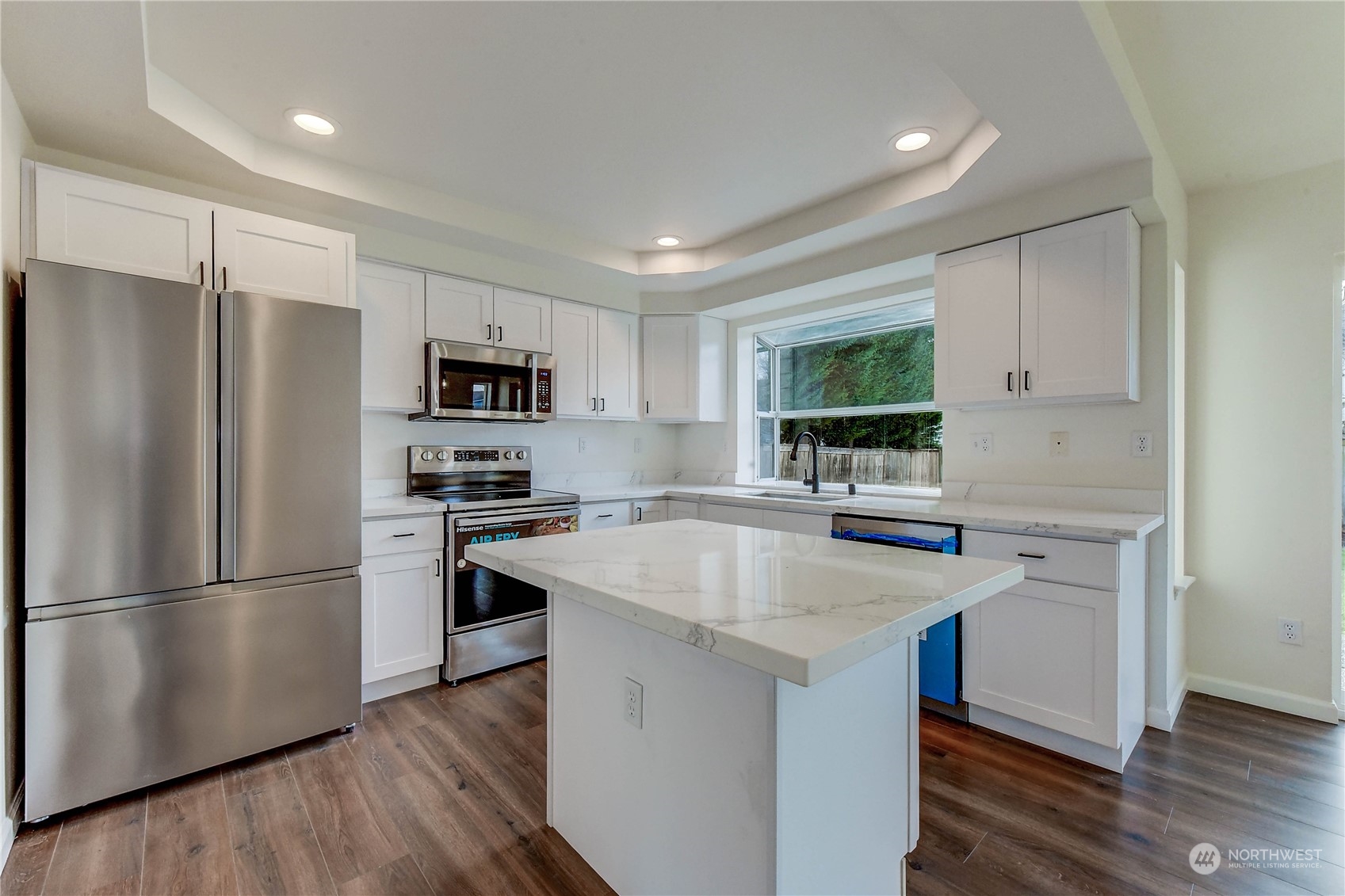 4407 Northeast 6th Place Renton, WA 98059 - Photo 8 of 25 a kitchen with kitchen island a refrigerator wooden floor and a sink