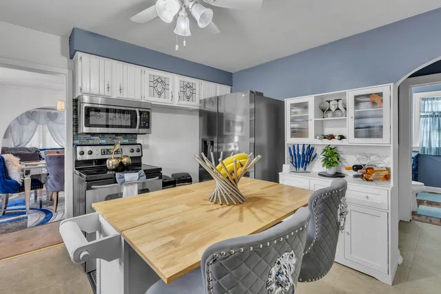 a living room with stainless steel appliances furniture a chandelier and a kitchen view