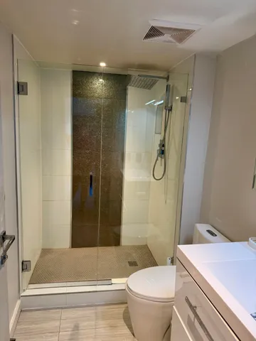 a bathroom with a granite countertop toilet a sink and shower