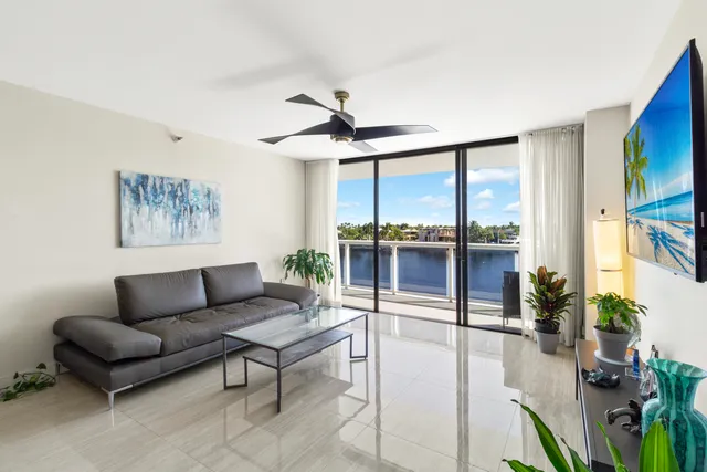a living room with furniture a ceiling fan and a large window