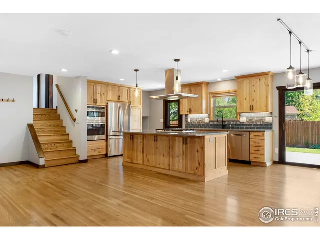 a kitchen with stainless steel appliances refrigerator wooden floor and window