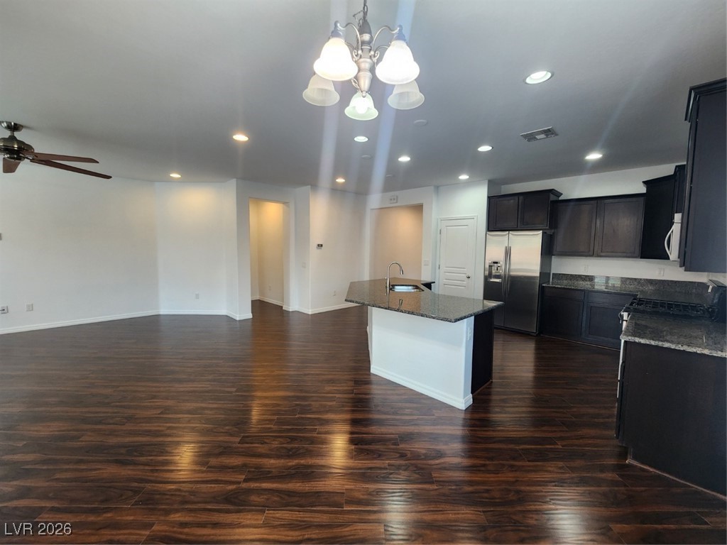 7022 Cordite Road Las Vegas, NV 89178 - Photo 10 of 51 Kitchen with dark stone countertops, white refrigerator, dark wood-type flooring, a kitchen island with sink, and pendant lighting