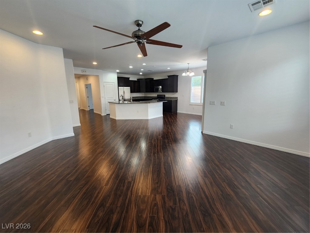 7022 Cordite Road Las Vegas, NV 89178 - Photo 12 of 51 Unfurnished living room with dark wood-style floors, recessed lighting, a ceiling fan, and a chandelier