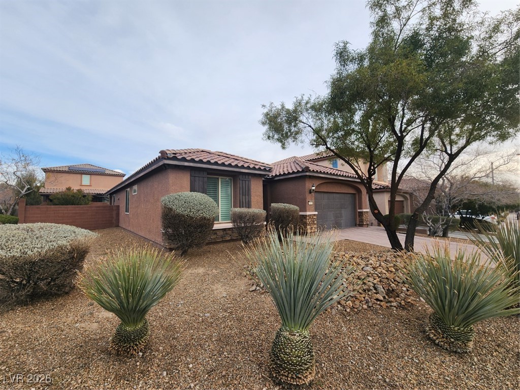 7022 Cordite Road Las Vegas, NV 89178 - Photo 2 of 51 Mediterranean / spanish house featuring stucco siding, stone siding, a tile roof, driveway, and an attached garage