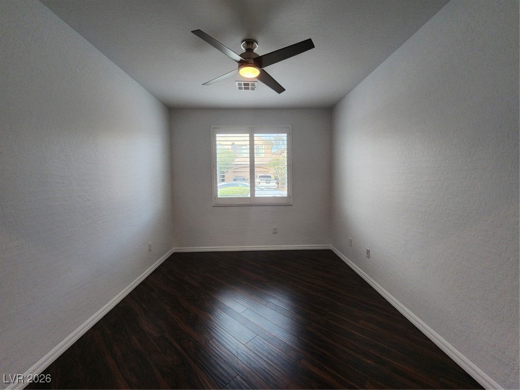 7022 Cordite Road Las Vegas, NV 89178 - Photo 26 of 51 Empty room with a textured wall, dark wood-type flooring, and ceiling fan