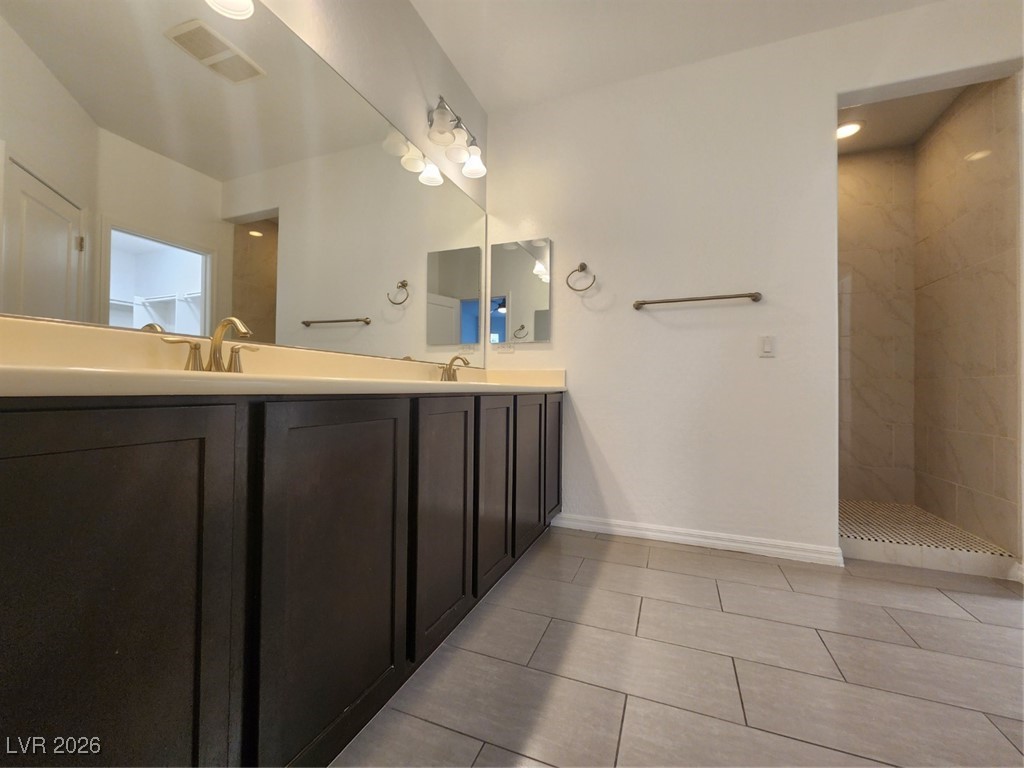 7022 Cordite Road Las Vegas, NV 89178 - Photo 32 of 51 Full bathroom featuring double vanity, a walk in shower, and light tile patterned floors