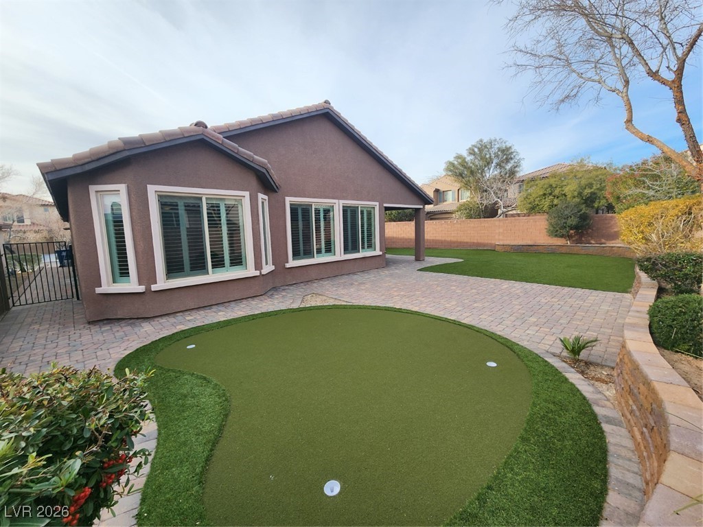 7022 Cordite Road Las Vegas, NV 89178 - Photo 43 of 51 Back of property with a putting green, a patio area, a fenced backyard, and stucco siding