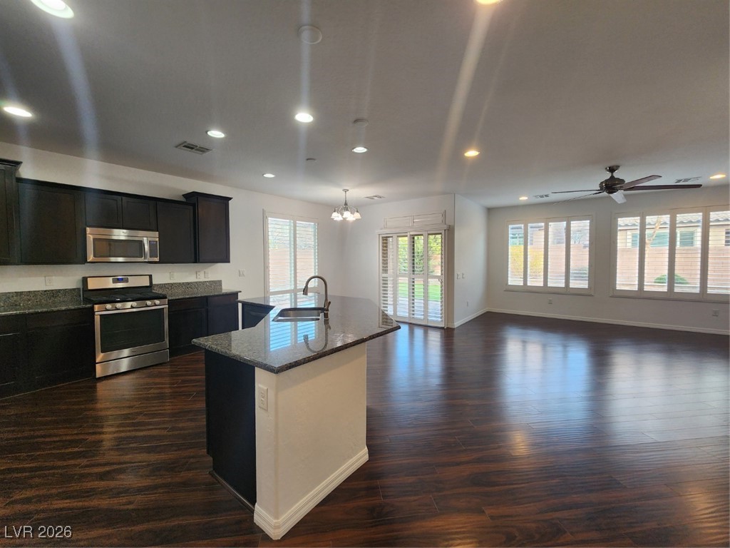 7022 Cordite Road Las Vegas, NV 89178 - Photo 50 of 51 Kitchen featuring stove, decorative light fixtures, dark stone countertops, a kitchen island with sink, and open floor plan