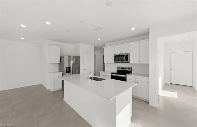 a kitchen with stainless steel appliances a stove top oven a sink a refrigerator and white cabinets