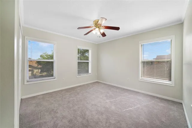 an empty room with windows and fan