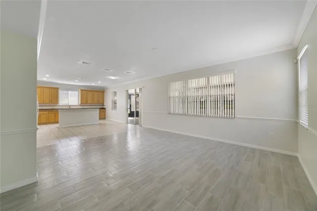 a view of empty room with wooden floor and kitchen view