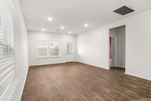 an empty room with wooden floor and windows