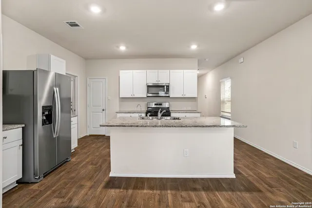 a large kitchen with stainless steel appliances granite countertop a stove a refrigerator a sink and dishwasher with wooden floor