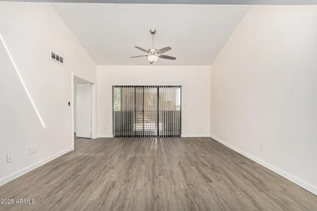 an empty room with a ceiling fan and wooden floor
