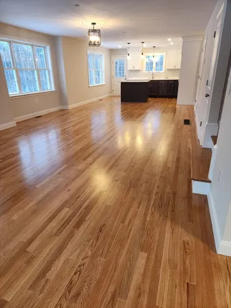 a view of a living room with wooden floor and a kitchen