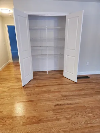 a view of an empty room with wooden floor and closet