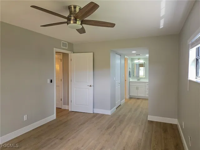 a view of empty room with wooden floor and fan