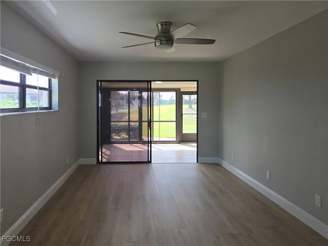 a view of an empty room with a window and wooden floor