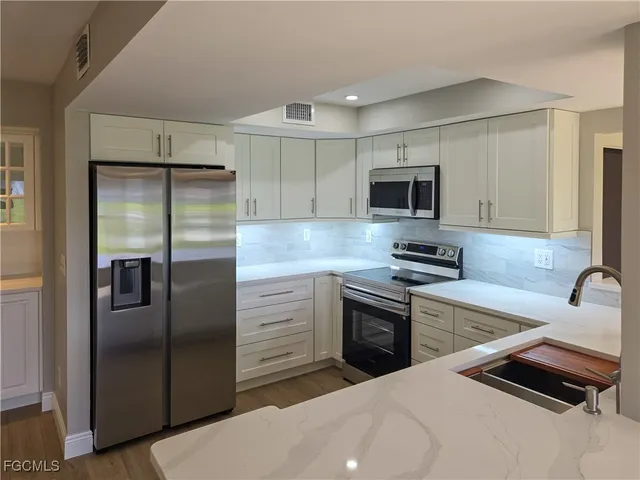 a kitchen with stainless steel appliances granite countertop a refrigerator and a stove top oven