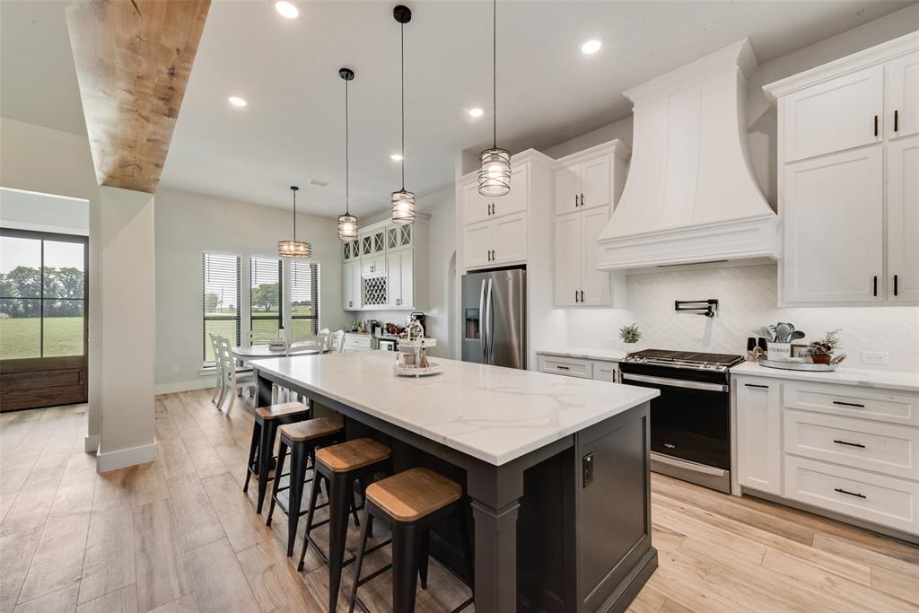 12880 Pruett Road Krum, TX 76249 - Photo 7 of 27 a kitchen with granite countertop a table chairs stainless steel appliances and wooden floor