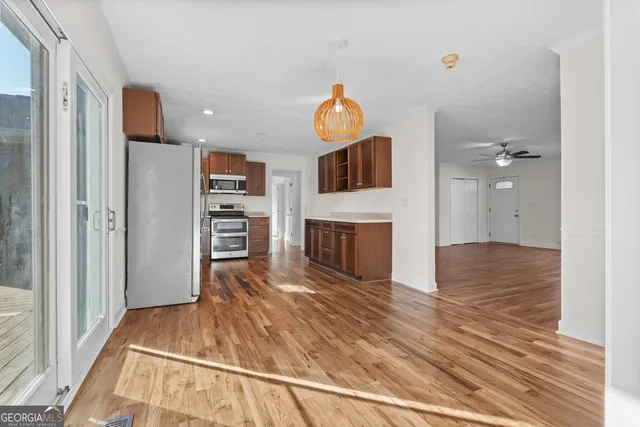 a view of a livingroom with a fireplace a ceiling fan and wooden floor