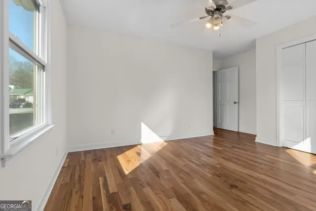 a view of empty room with wooden floor and fan