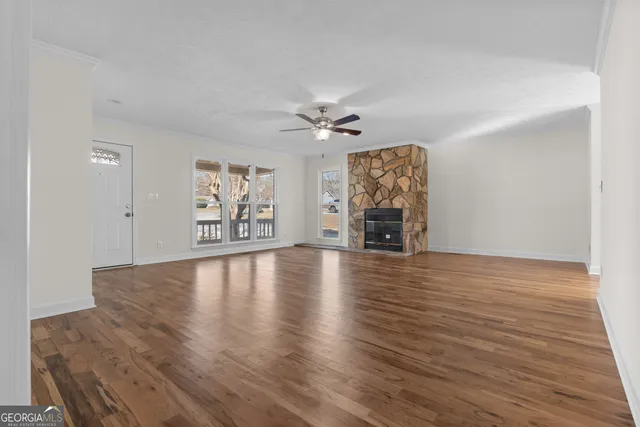 an empty room with wooden floor chandelier fan and windows
