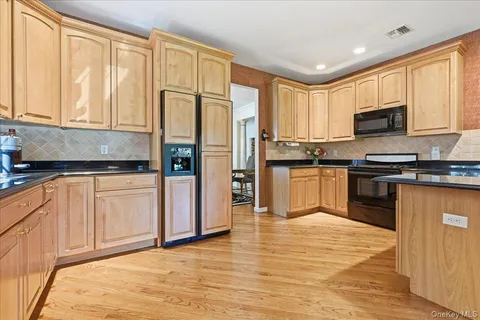 a kitchen with stainless steel appliances granite countertop a refrigerator a sink dishwasher a stove with wooden cabinets and floor