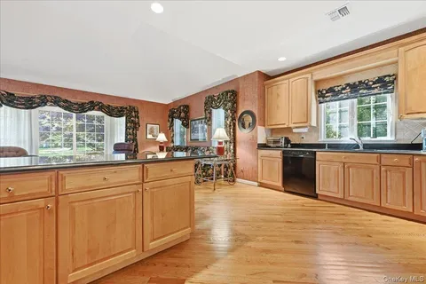 a kitchen with stainless steel appliances granite countertop a stove top oven a sink dishwasher and white cabinets with wooden floor