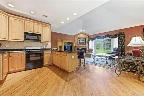 a kitchen with stainless steel appliances a stove top oven a sink dishwasher and white cabinets with wooden floor