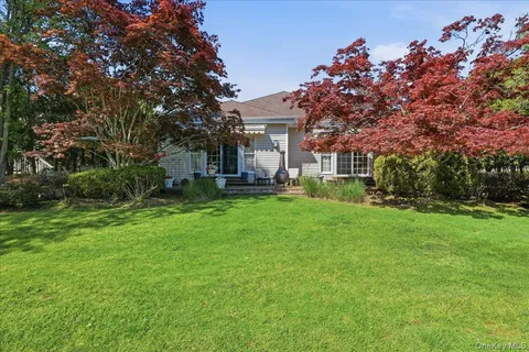 a front view of a house with a garden and trees