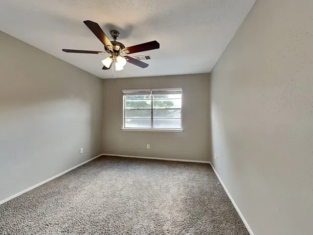 an empty room with windows and fan