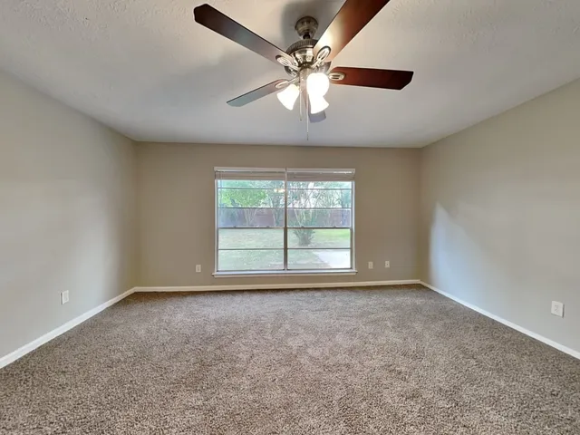 an empty room with windows and ceiling fan