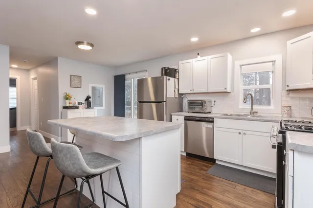 a kitchen with stainless steel appliances granite countertop a white cabinets and a refrigerator