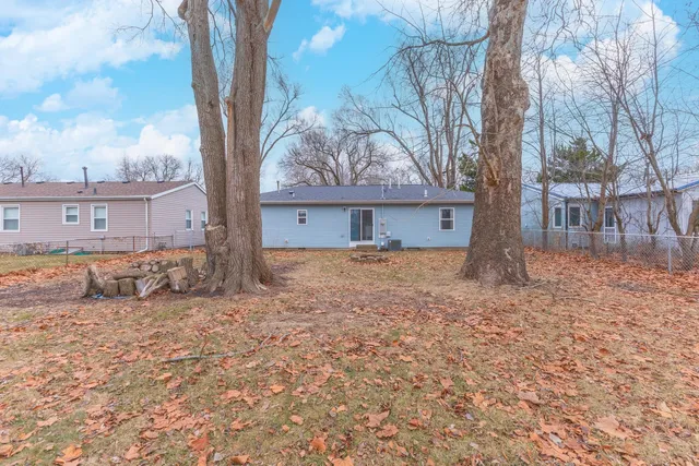 a backyard of a house with large trees and outdoor seating