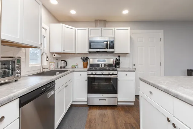 a kitchen with stainless steel appliances granite countertop a sink a stove a refrigerator and cabinets