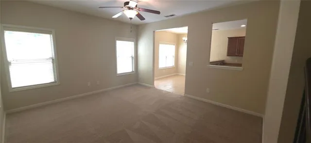en empty room with windows and chandelier fan