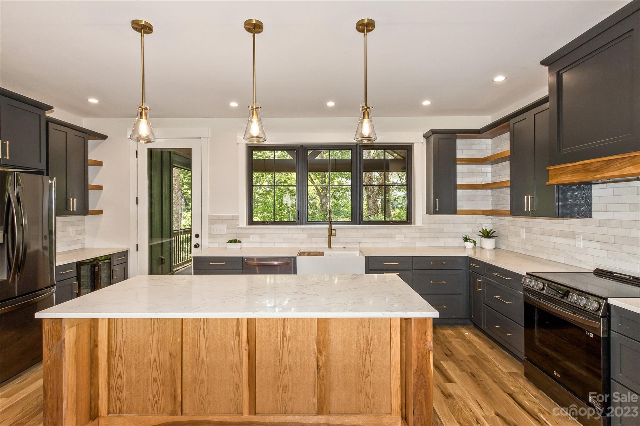 159 Gashes Creek Road Asheville, NC 28805 - Photo 15 of 48 a kitchen with stainless steel appliances a sink a stove a refrigerator a center island and a wooden floor